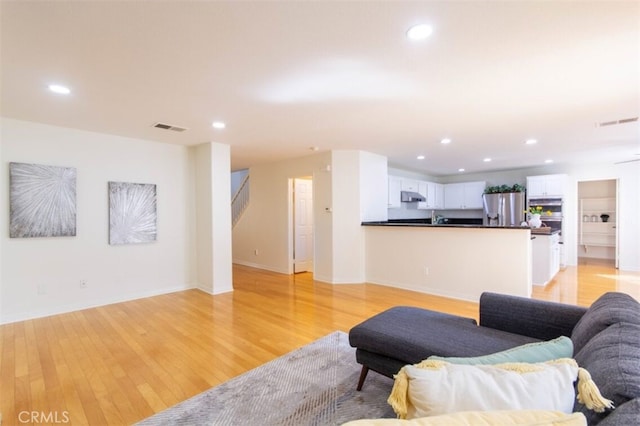 living room with light wood-style floors, recessed lighting, and visible vents