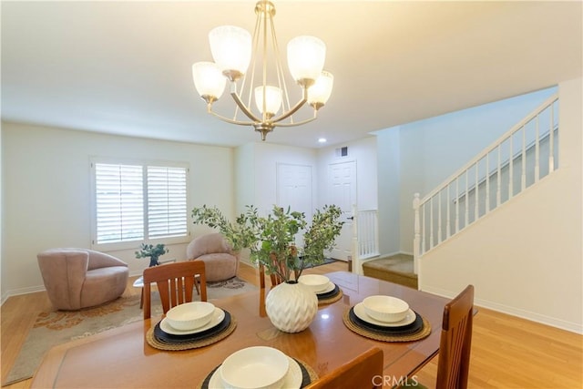 dining area featuring baseboards, visible vents, stairway, light wood-type flooring, and a notable chandelier