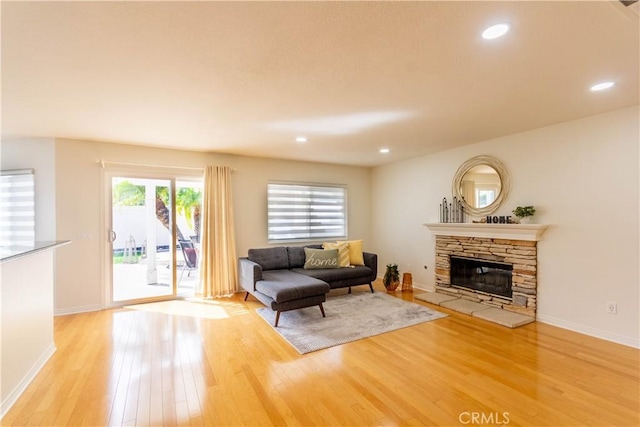 living area featuring recessed lighting, light wood-type flooring, a fireplace, and baseboards