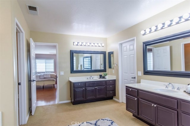 bathroom with visible vents, two vanities, a sink, and ensuite bathroom