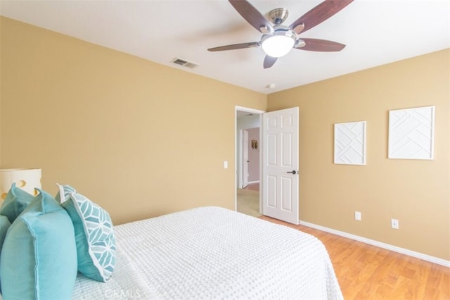 bedroom featuring a ceiling fan, light wood-style flooring, visible vents, and baseboards