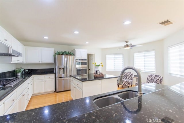 kitchen featuring visible vents, appliances with stainless steel finishes, dark stone countertops, white cabinetry, and a sink