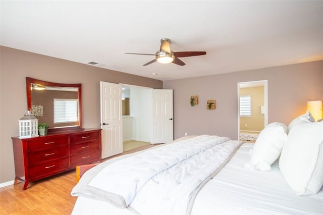 bedroom with baseboards, visible vents, a ceiling fan, ensuite bath, and light wood-type flooring