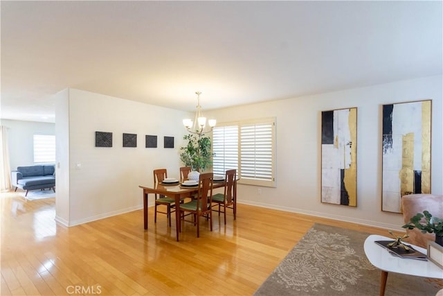 dining area with a chandelier, a wealth of natural light, and light wood-style flooring