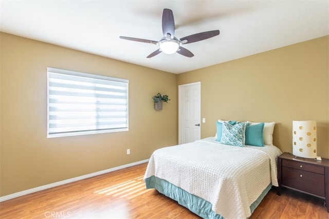 bedroom with ceiling fan, baseboards, and wood finished floors