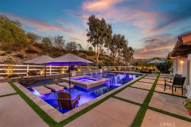 view of swimming pool featuring an infinity pool, an in ground hot tub, a patio area, and fence