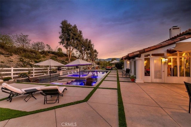 pool at dusk featuring an in ground hot tub, fence, a fenced in pool, and a patio