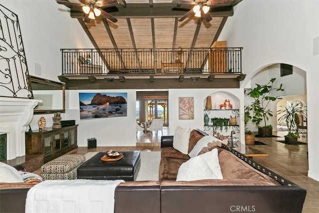 living room featuring high vaulted ceiling, arched walkways, ceiling fan, and stairs