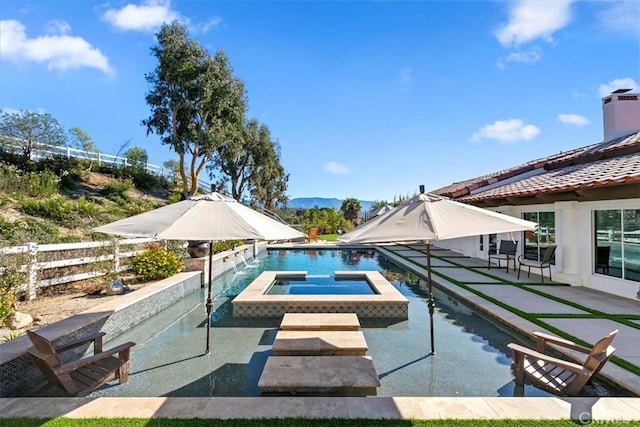 pool with an in ground hot tub, a patio area, fence, and a mountain view