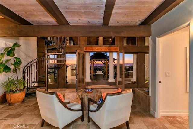 interior space featuring wooden ceiling, stairs, stone finish floor, and beamed ceiling