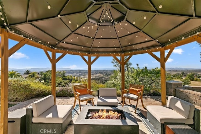 view of patio / terrace featuring a gazebo, an outdoor living space with a fire pit, and a mountain view