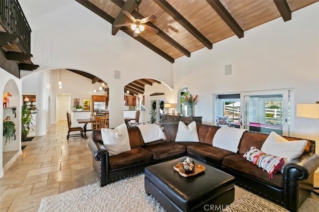 living room with arched walkways, high vaulted ceiling, wood ceiling, beamed ceiling, and stone tile flooring