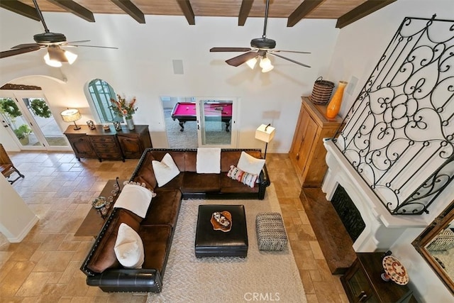 living room with stairs, a high ceiling, arched walkways, and beam ceiling