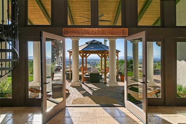 interior space featuring stone tile floors, stairs, decorative columns, and french doors