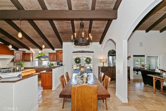 dining space featuring arched walkways, wood ceiling, stone tile flooring, french doors, and a wealth of natural light