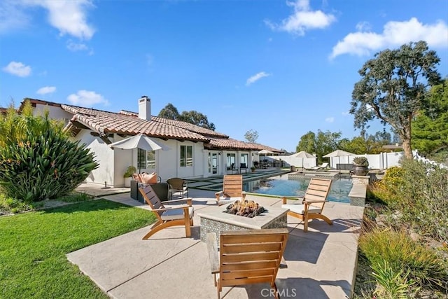 exterior space with a patio, an outdoor fire pit, fence, a tiled roof, and a chimney