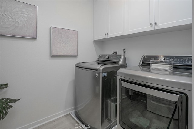 laundry room featuring baseboards, light tile patterned floors, cabinet space, and washer and dryer