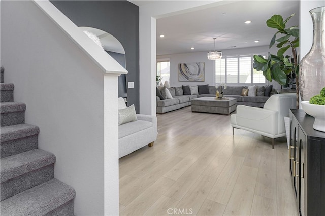 living area featuring recessed lighting, stairway, light wood finished floors, and an inviting chandelier