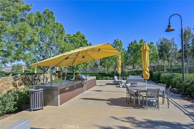 view of patio / terrace with fence, grilling area, exterior kitchen, and outdoor dining space