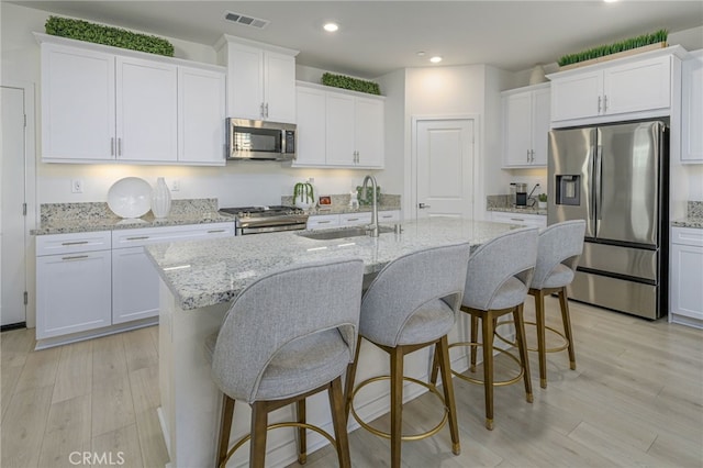 kitchen featuring appliances with stainless steel finishes, visible vents, a sink, and light wood finished floors