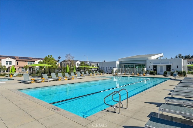 pool with a patio area, fence, and a residential view