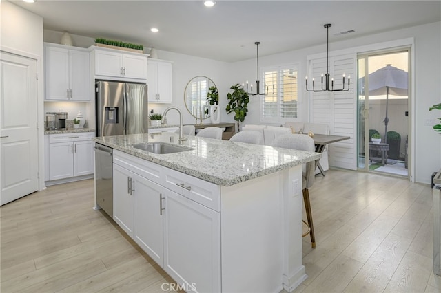 kitchen featuring light wood finished floors, visible vents, appliances with stainless steel finishes, an inviting chandelier, and a sink