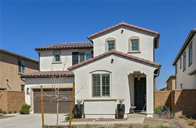 mediterranean / spanish-style house featuring an attached garage, fence, concrete driveway, and stucco siding