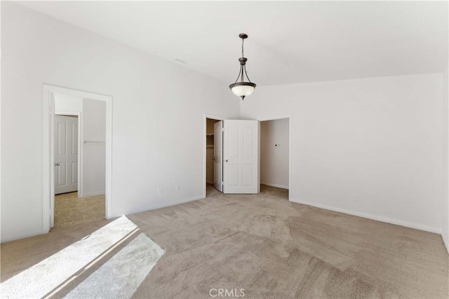 unfurnished bedroom featuring carpet floors, a spacious closet, and baseboards