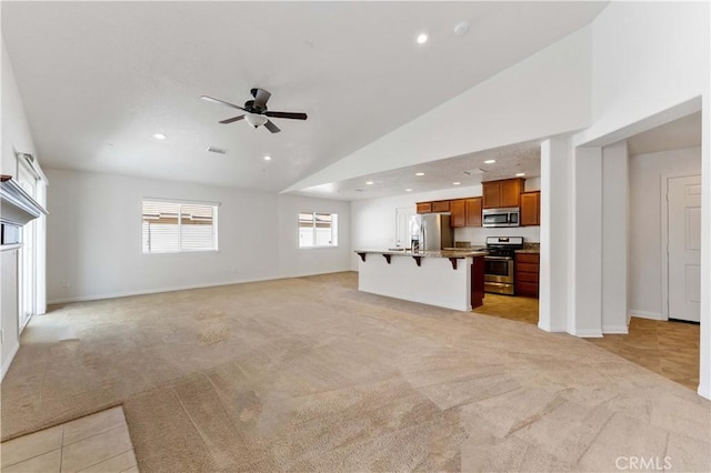 unfurnished living room with ceiling fan, high vaulted ceiling, recessed lighting, light carpet, and baseboards