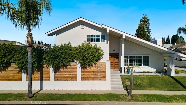 view of front of house featuring fence and stucco siding