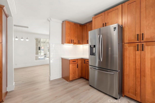 kitchen featuring brown cabinets, stainless steel refrigerator with ice dispenser, tasteful backsplash, light countertops, and light wood-style floors