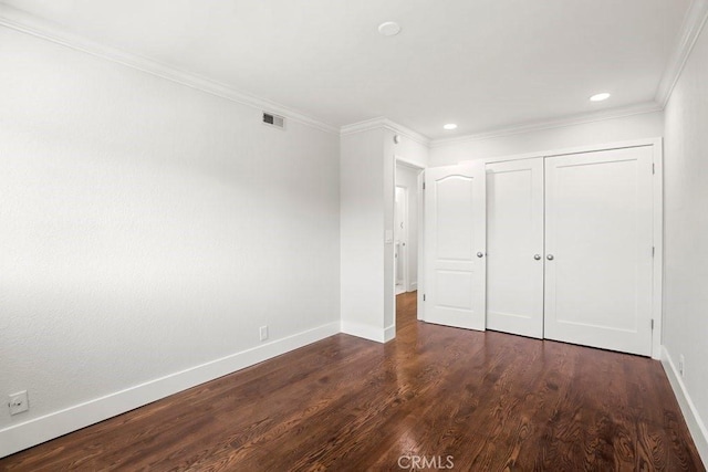 unfurnished bedroom featuring baseboards, visible vents, dark wood-type flooring, crown molding, and a closet