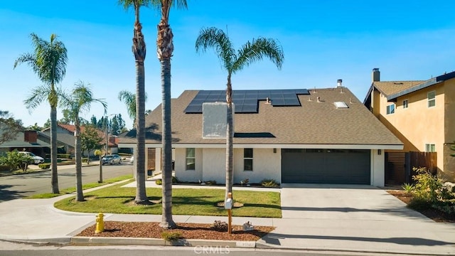 view of front of house featuring stucco siding, solar panels, a front yard, a garage, and driveway