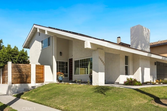 view of front of property with a chimney, stucco siding, an attached garage, fence, and a front lawn