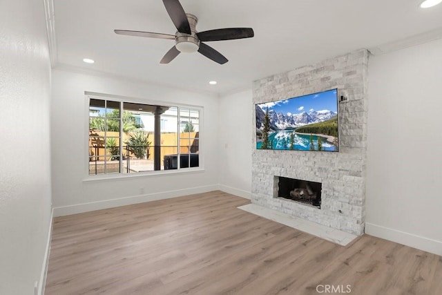 unfurnished living room featuring baseboards, ornamental molding, wood finished floors, a stone fireplace, and recessed lighting