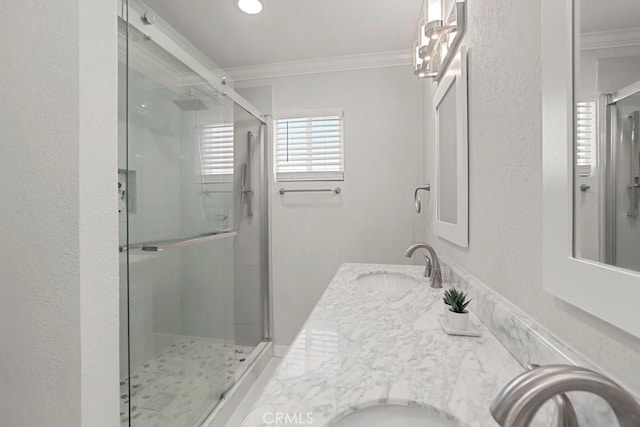 full bathroom featuring a sink, a stall shower, double vanity, and crown molding