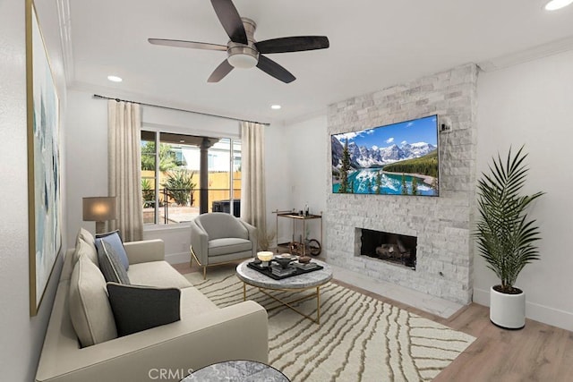 living room featuring baseboards, ornamental molding, wood finished floors, a fireplace, and recessed lighting