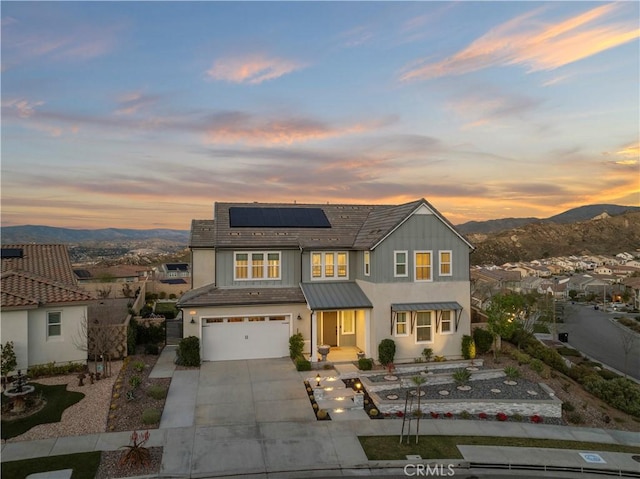 view of front of home with solar panels, an attached garage, a mountain view, fence, and driveway