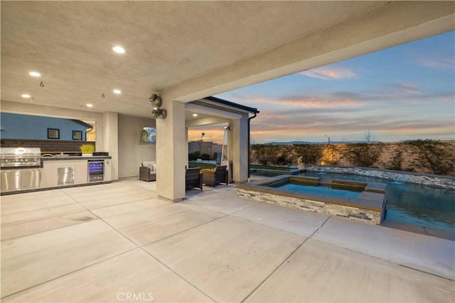 view of patio featuring an outdoor pool, wine cooler, an in ground hot tub, a grill, and exterior kitchen