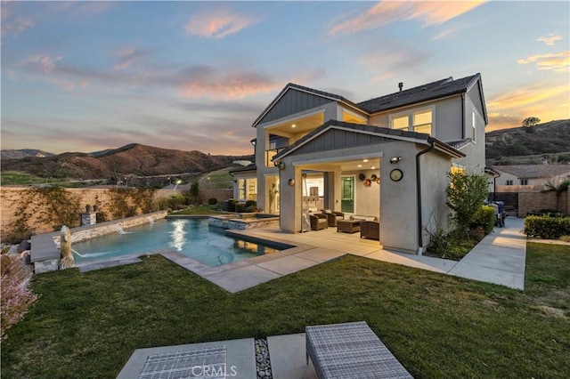 rear view of property with solar panels, a lawn, a patio, an outdoor hangout area, and a mountain view