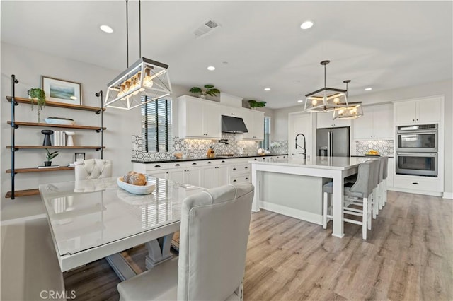 dining space with light wood-style flooring, visible vents, and recessed lighting