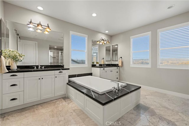 bathroom with a wealth of natural light, marble finish floor, a sink, and baseboards