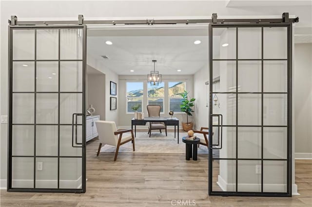 interior space featuring light wood finished floors, a barn door, visible vents, and recessed lighting