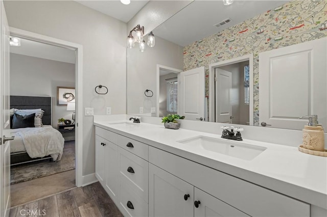 bathroom with wallpapered walls, ensuite bath, a sink, and wood finished floors