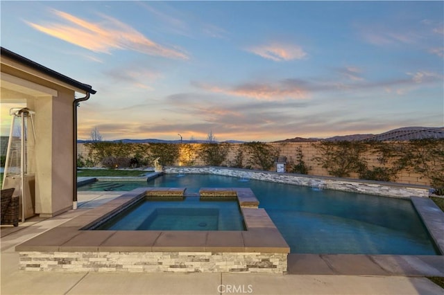 view of swimming pool with a pool with connected hot tub and a mountain view