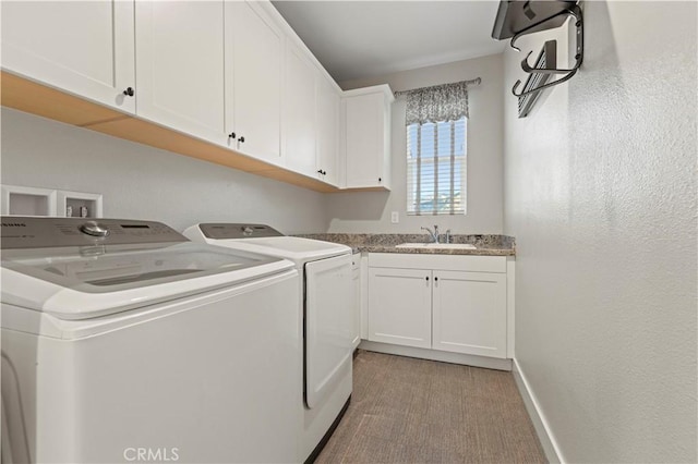 laundry area featuring cabinet space, baseboards, a sink, and independent washer and dryer