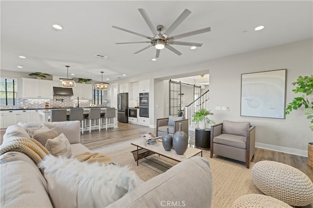 living room featuring light wood finished floors, stairway, visible vents, and recessed lighting