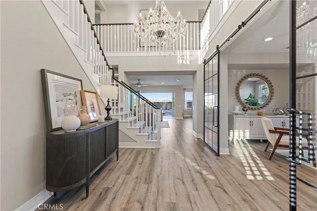 entrance foyer with stairs, a barn door, wood finished floors, and baseboards