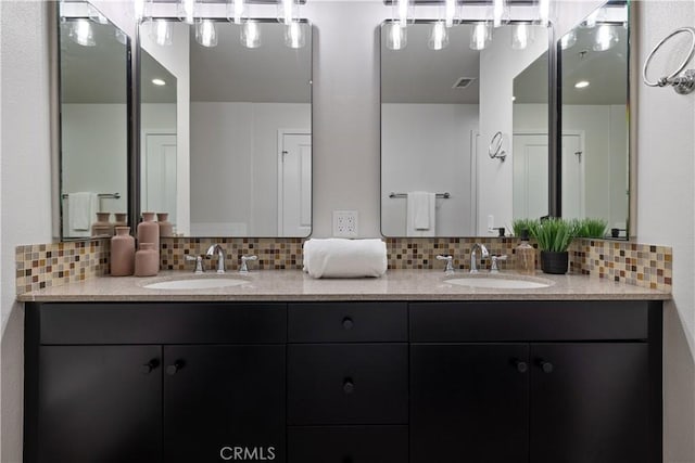 full bath with a sink, backsplash, and double vanity