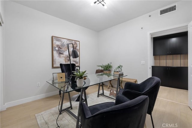 office with light wood-style flooring, visible vents, and baseboards